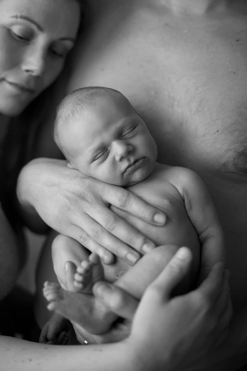 Newborn kuvauksessa vastasyntynyt vauva isän sylissä.