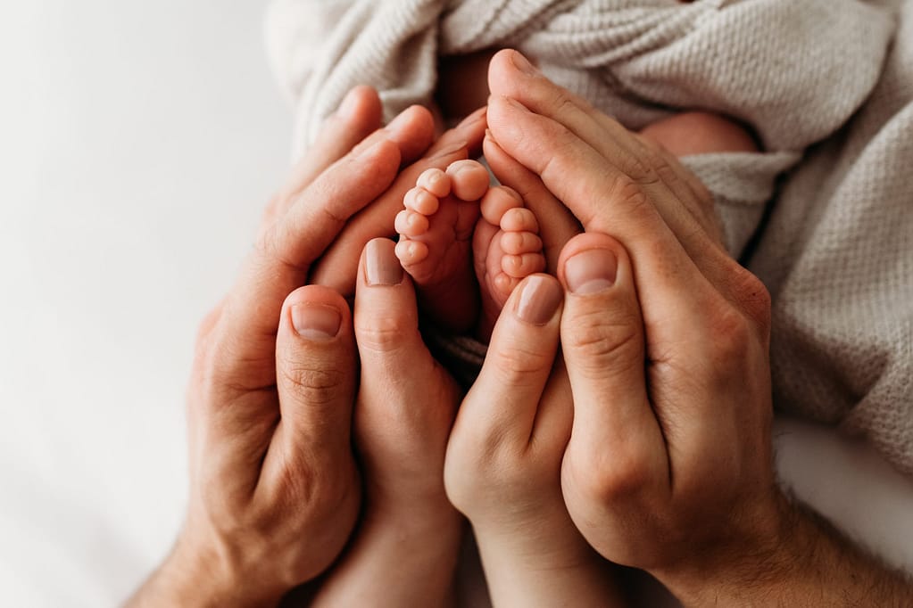 Vauvan pienet varpaat ja vanhempien kädet