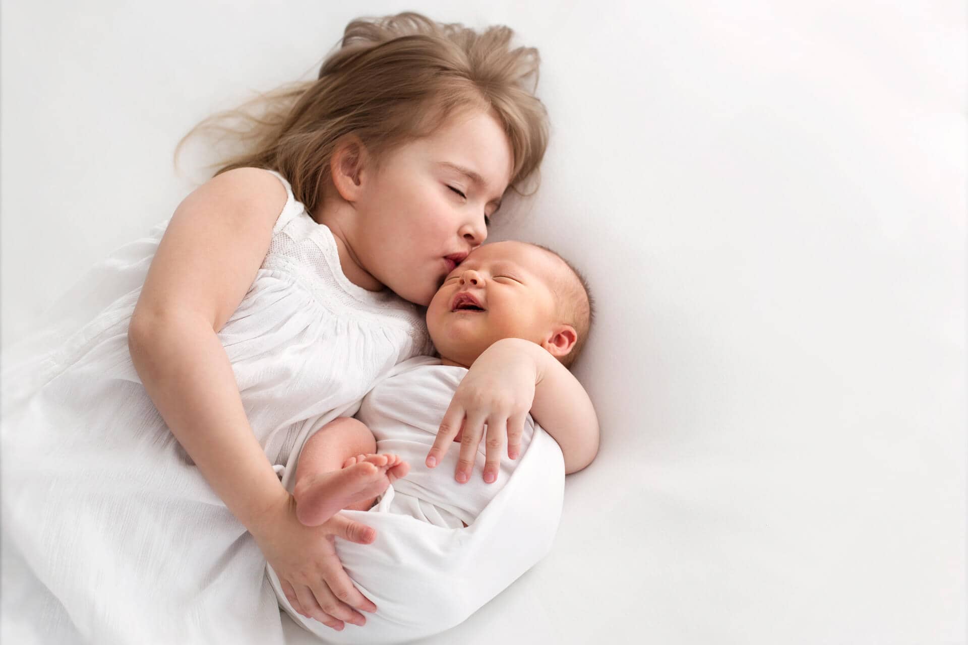 vastasyntynyt vauva isosiskon kanssa newborn kuvauksessa.